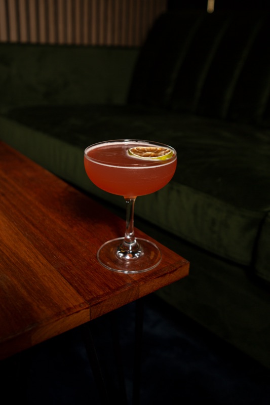 Cocktail on a wooden table edge, green lounge seating