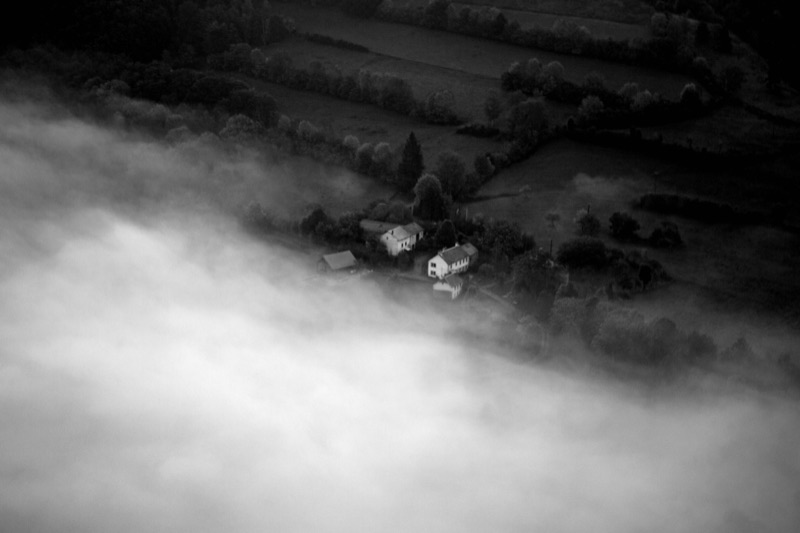 Farmhouse in the morning mist, aerial view, black and white