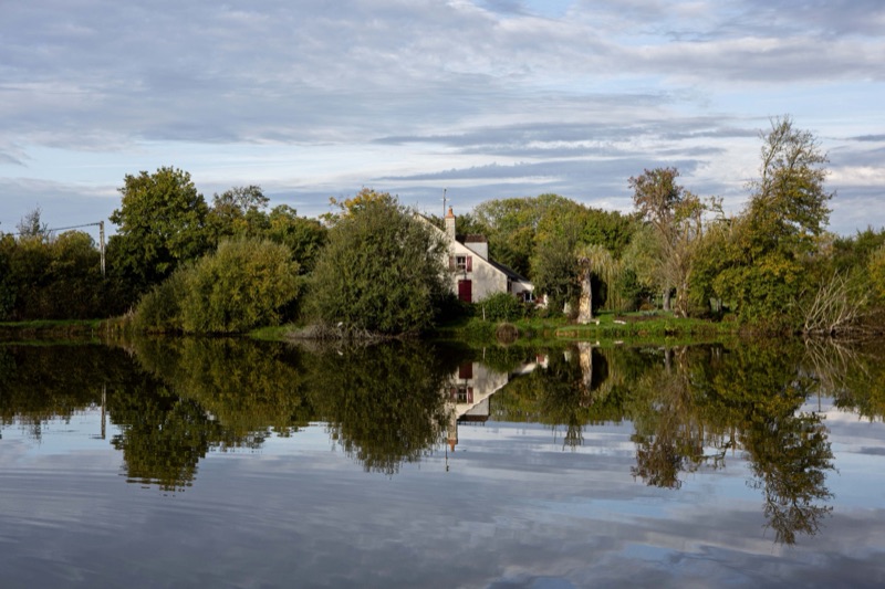 A house by the water, reflected in a still lake
