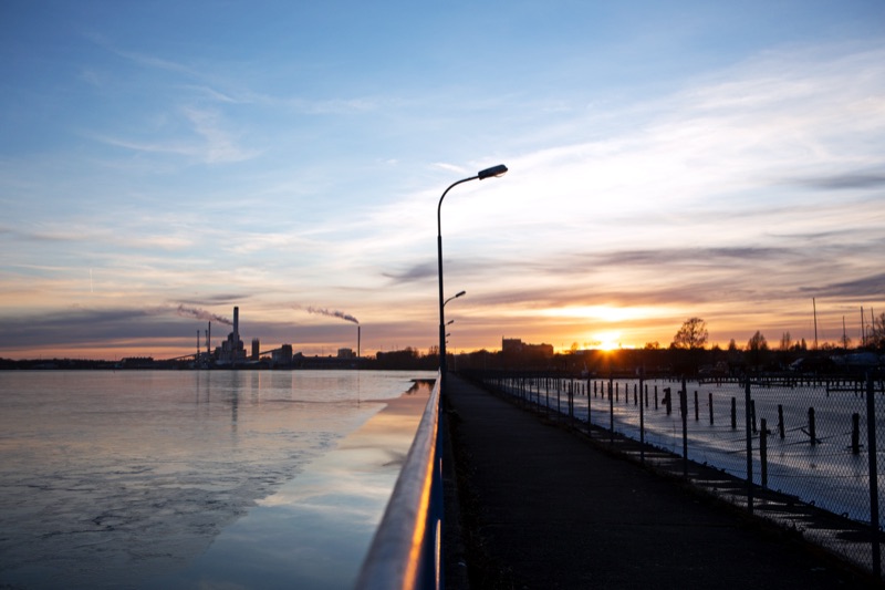 Sunset over the water, industrial skyline in the distance